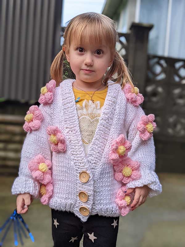Baby girl wearing a knit cardigan decorated with ten crochet flowers