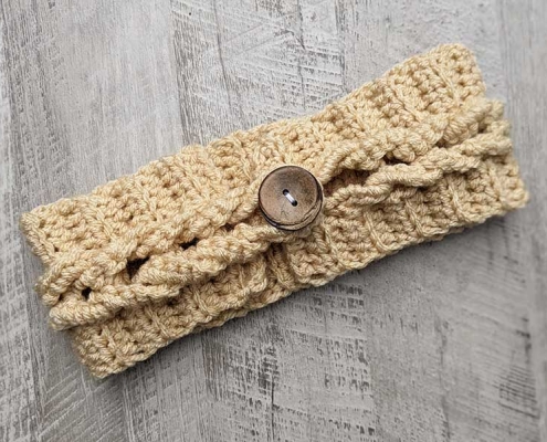 crochet cable headband with a decor button on the top