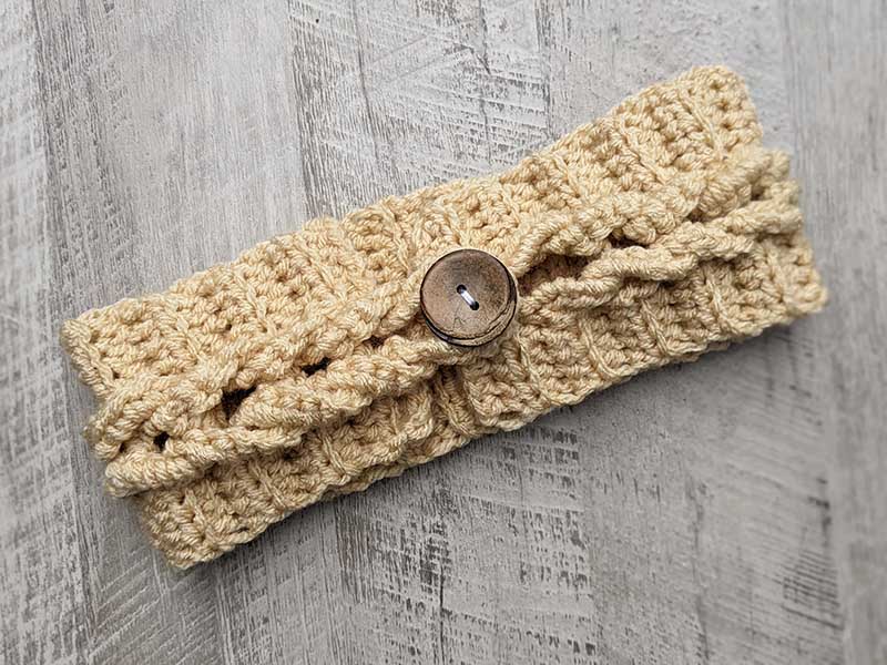 crochet cable headband with a decor button on the top