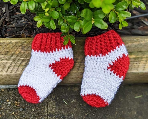 two crochet socks for a newborn baby next to each other