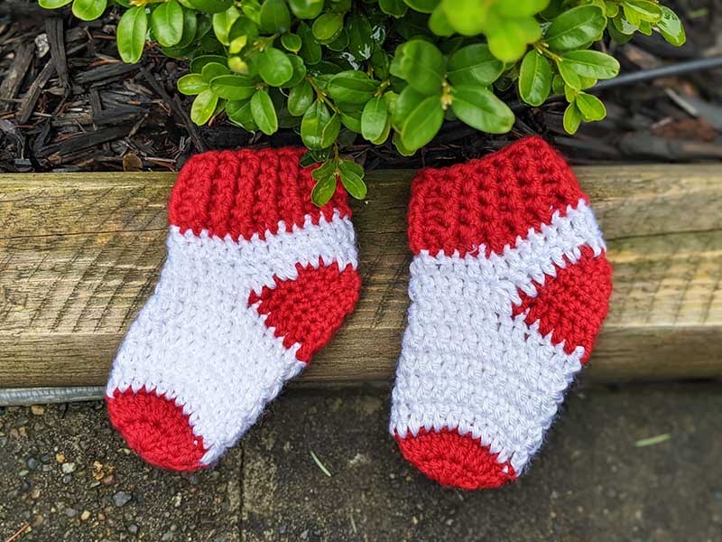 two crochet socks for a newborn baby next to each other