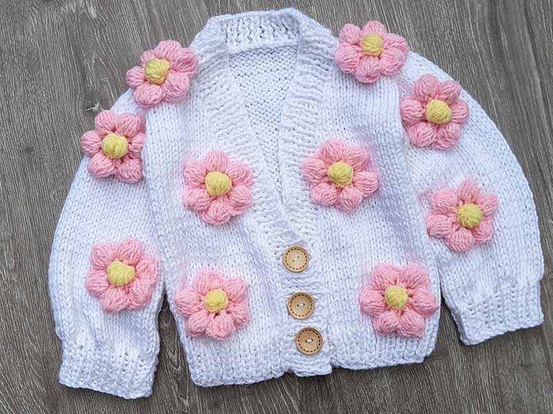 Knit baby cardigan embellished with ten crochet flowers made using puff stitch