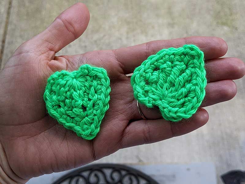 two green crochet leaves held on the hand