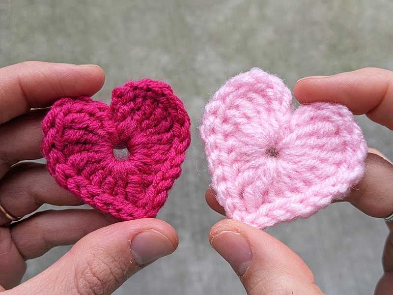 two tiny crochet hearts - one red and one pink coloured