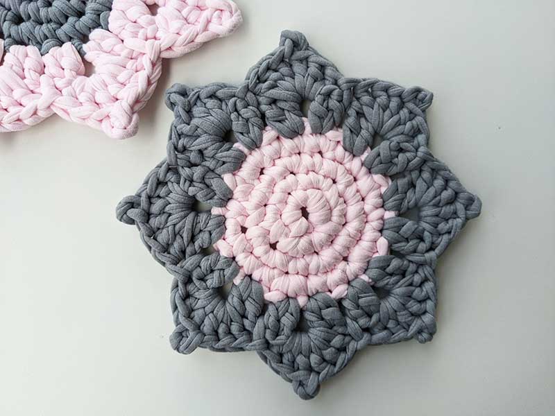 crochet sunflower hot pad with pink middle and gray leaves