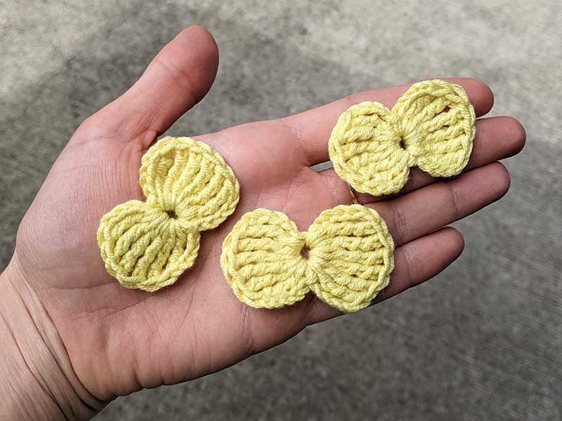 three yellow easy crochet bows on a hand