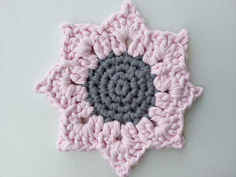 crochet sunflower hot pad with gray middle and pink leaves