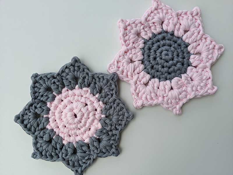 two crochet sunflower-shaped bicolored hot pads