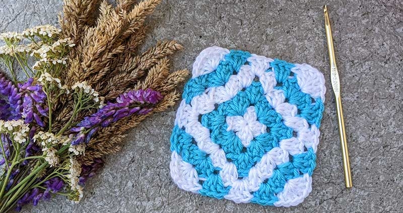 crochet granny square with blue diamond in the middle and arcs on the edges