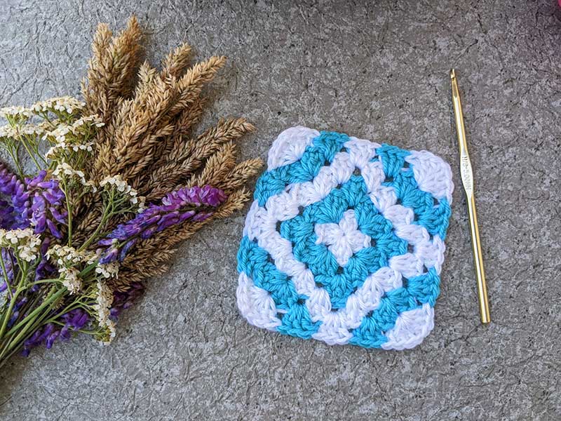 crochet granny square with blue diamond in the middle and arcs on the edges