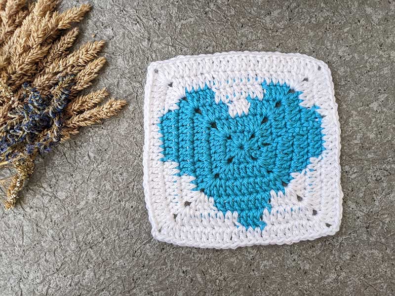 crochet granny square with blue heart and white canvas