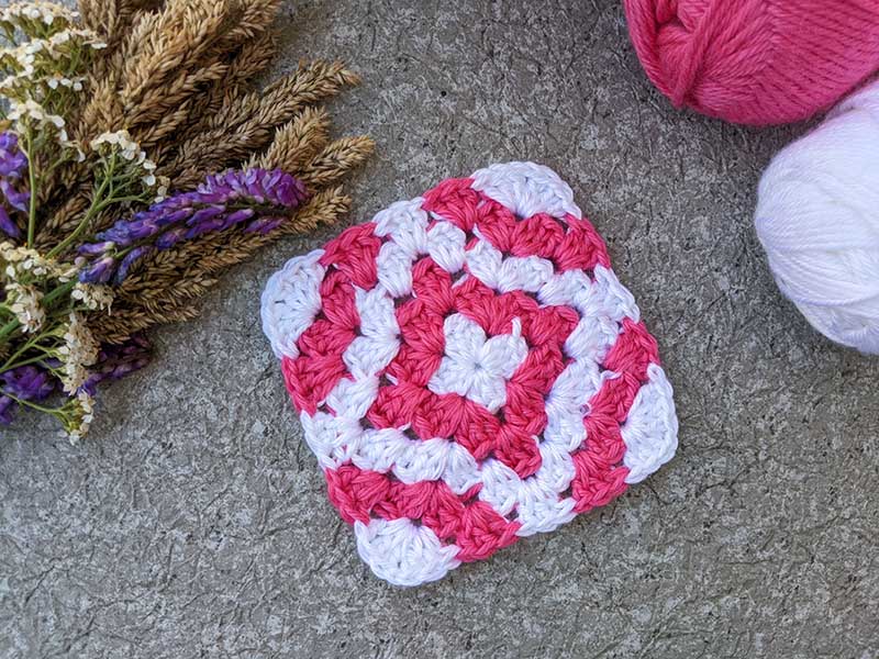 crochet granny square with the curved astroid-like shape of a red diamond and additional red curves on the edges