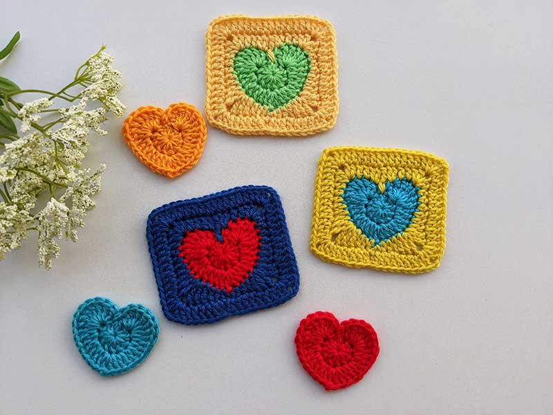 three crochet solid heart granny squares and three crochet hearts arranged in a composition