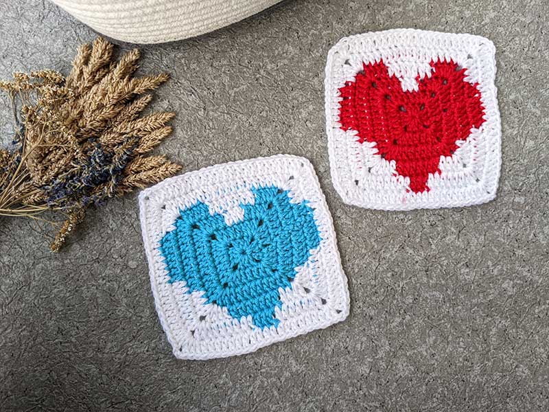 two crochet granny squares - one with blue and another one with red heart