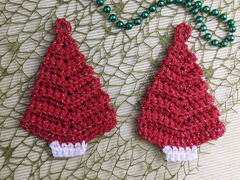 two crochet mini Christmas trees made with red and white yarn