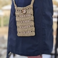 female model wears a crochet cellphone bag on a long handle