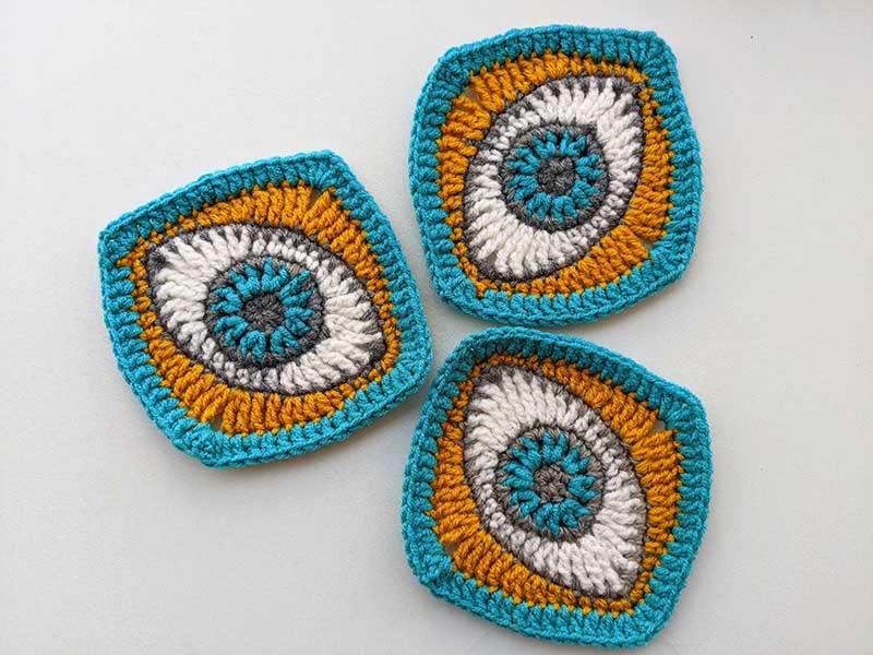 blue, white, gray, and yellow crochet eye granny square