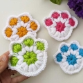 four crochet paw print coasters made in different colors - green, orange, red, and blue