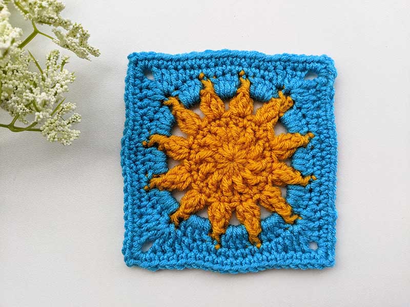 large-sized crochet granny square made with blue and orange yarn