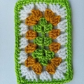 crochet lace granny rectangle made with three different yarn colors - green, yellow, and white.