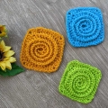 three mono-coloured crochet spiral granny squares - blue, yellow/orange, and light green
