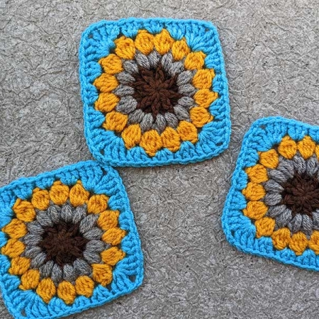 three crochet sunburst granny squares arranged in a composition