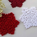 two crochet snowflakes - one is made using white color yarn and the other one is made using red color yarn