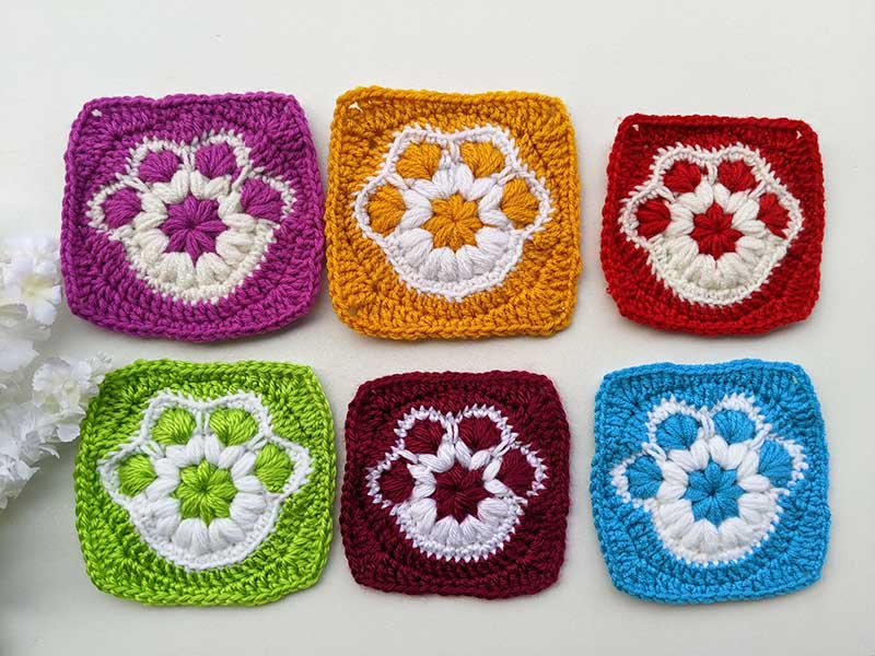six crochet paw print granny squares arranged in two rows with three squares in each