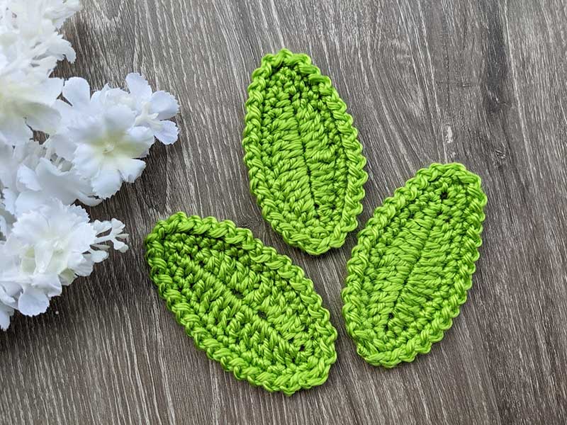 three crochet oval leaves arrangement next to a white flower