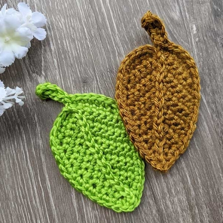 two crochet autumn fall leaves made with green and brown yarn