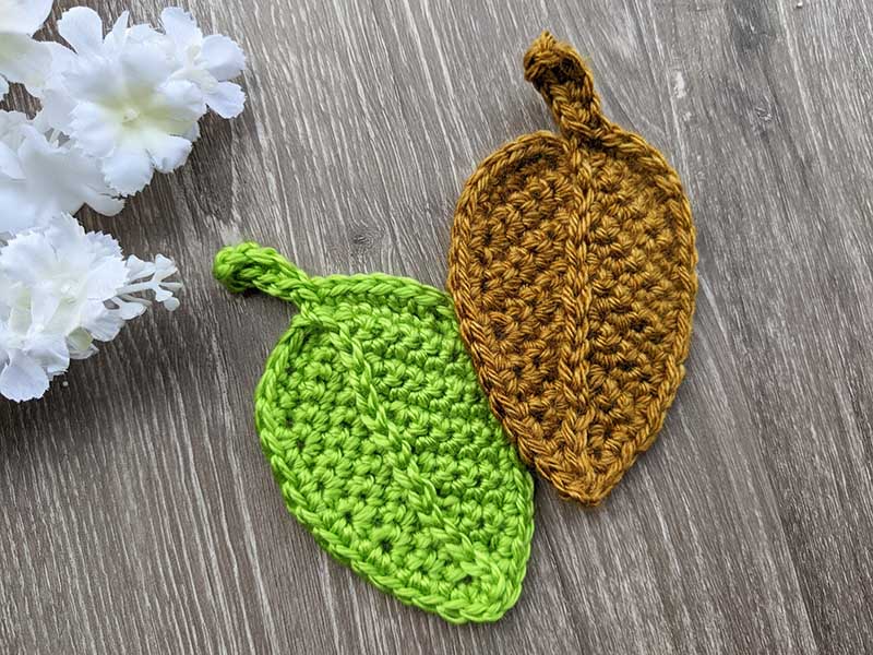two crochet autumn fall leaves made with green and brown yarn