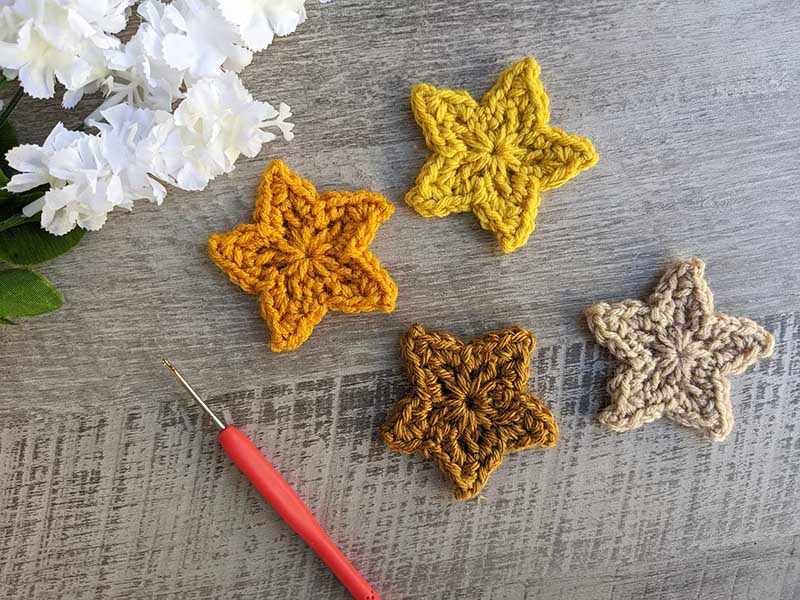 four crochet five-point stars made in different shades of yellow and arranged two by two
