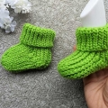 crochet baby booties - one on the mannequin foot and the other one lays flat next to it