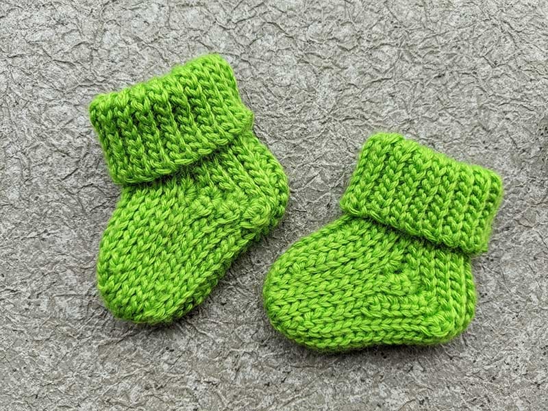 two crochet baby booties arranged to mimic a baby step