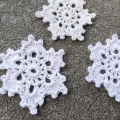 close up view of three crochet lace snowflakes