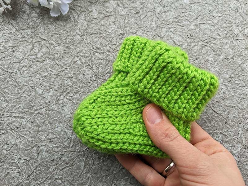two crochet baby booties made with green yarn
