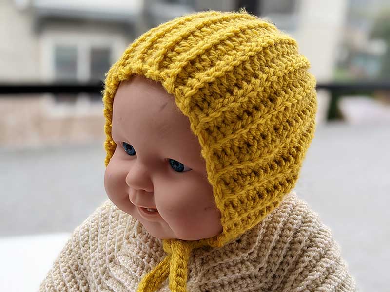 crochet baby bonnet on a doll mannequin - left side view