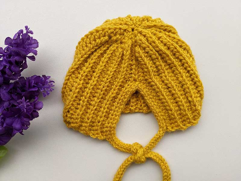 crochet baby bonnet on a flat surface - back side view