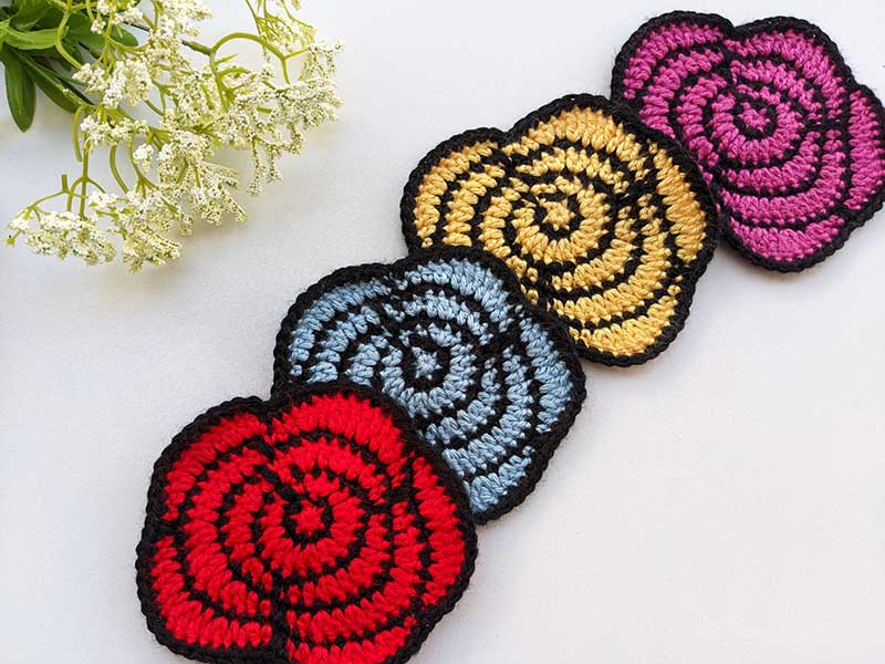 four crochet roses arranged in a diagonal line