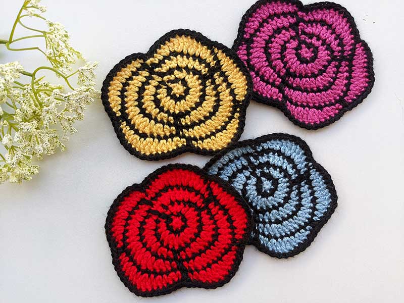 four crochet two-color roses arranged in two rows - pink, yellow, blue, and red