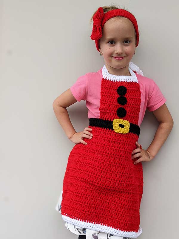 crochet Christmas headband and apron set on a kid model - zoomed-out view