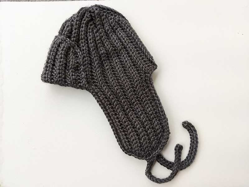 crochet trapper hat for men and women - side view on a flat surface