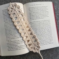 crochet triangular lace bookmark with a book on the background