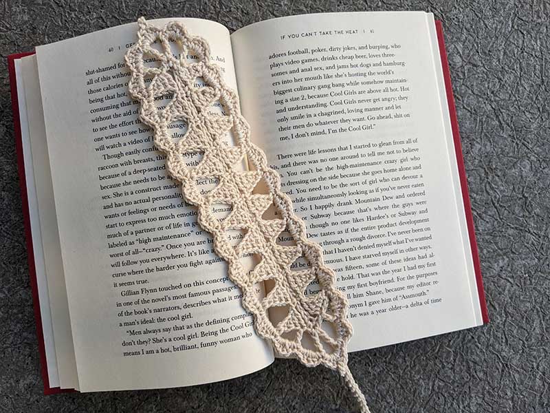 crochet triangular lace bookmark with a book on the background