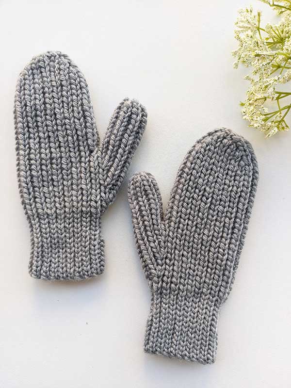 crochet woman's flat mittens on a flat surface with back (outer) side facing camera