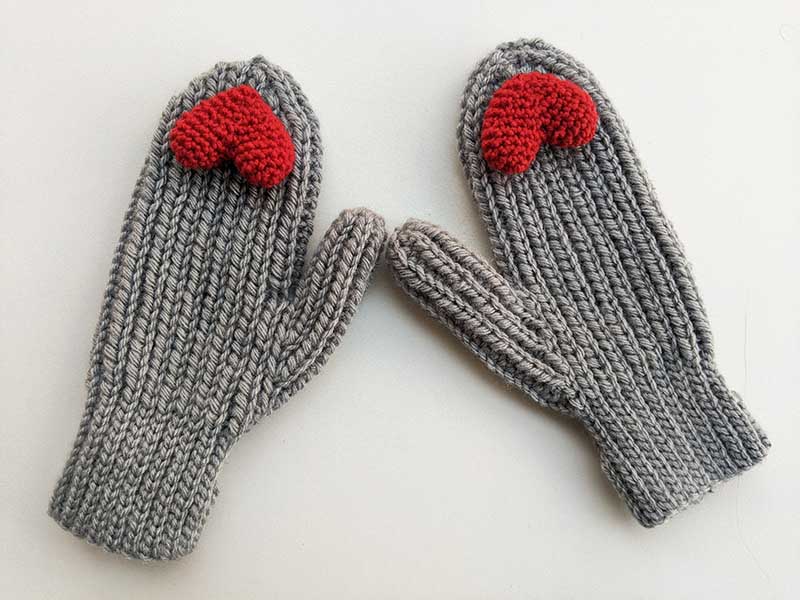 crochet woman's flat mittens with small red heart decor elements on the peak of each mitten 