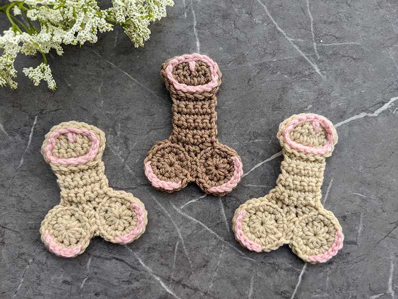 three crochet willies of different colors - one dark brown in the middle and two light brown one on each side