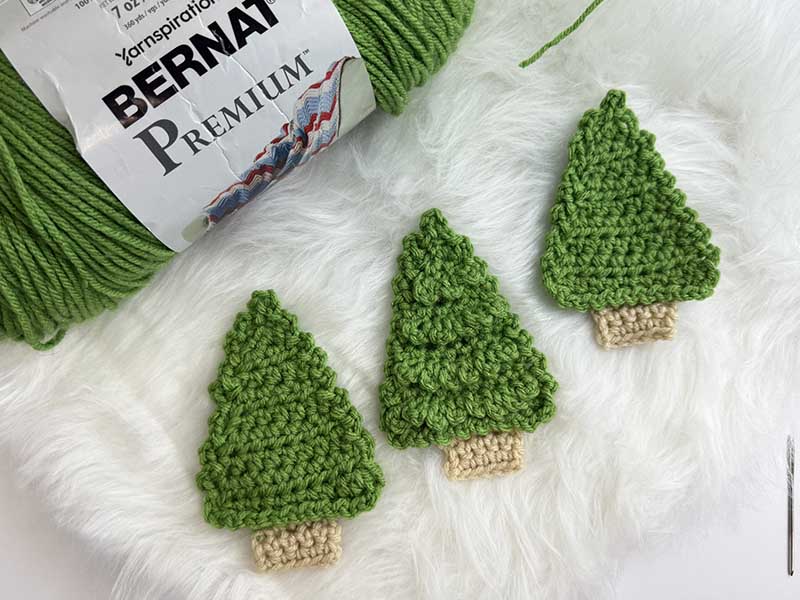 three crochet Christmas trees laying in a row
