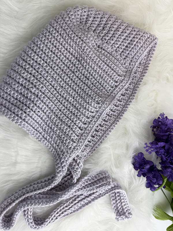crochet hood style bonnet on flat surface