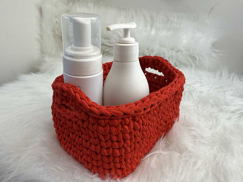 crochet red rectangular basket with shampoo bottles inside
